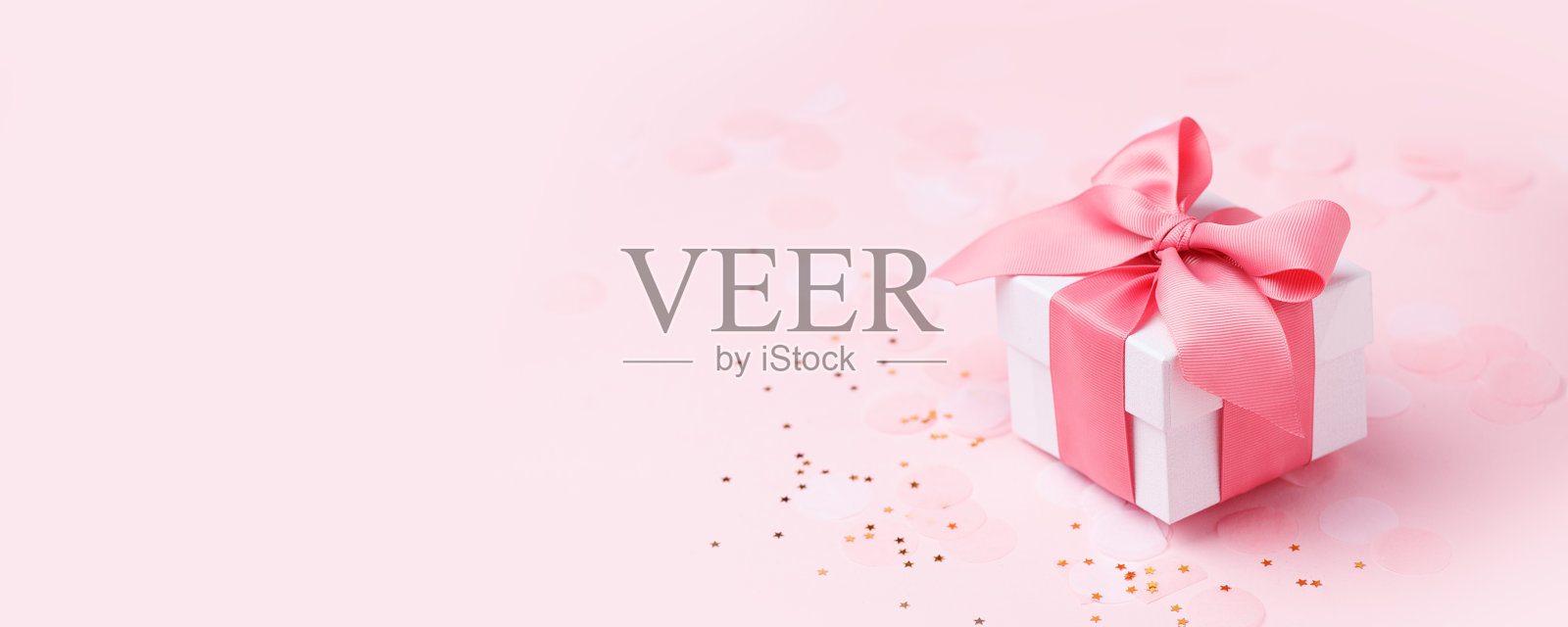 粉色背景的节日礼物，白色缎子蝴蝶结，丝带。情人节，妇女节快乐，母亲节，生日，婚礼，圣诞节。文字，横幅，传单的空间照片摄影图片