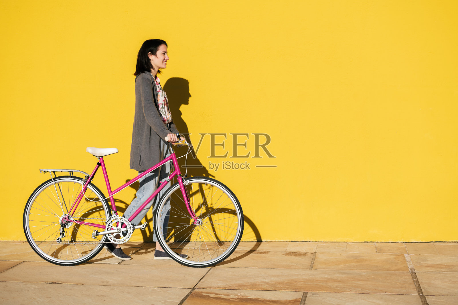 女孩骑着自行车走在黄色的墙前照片摄影图片