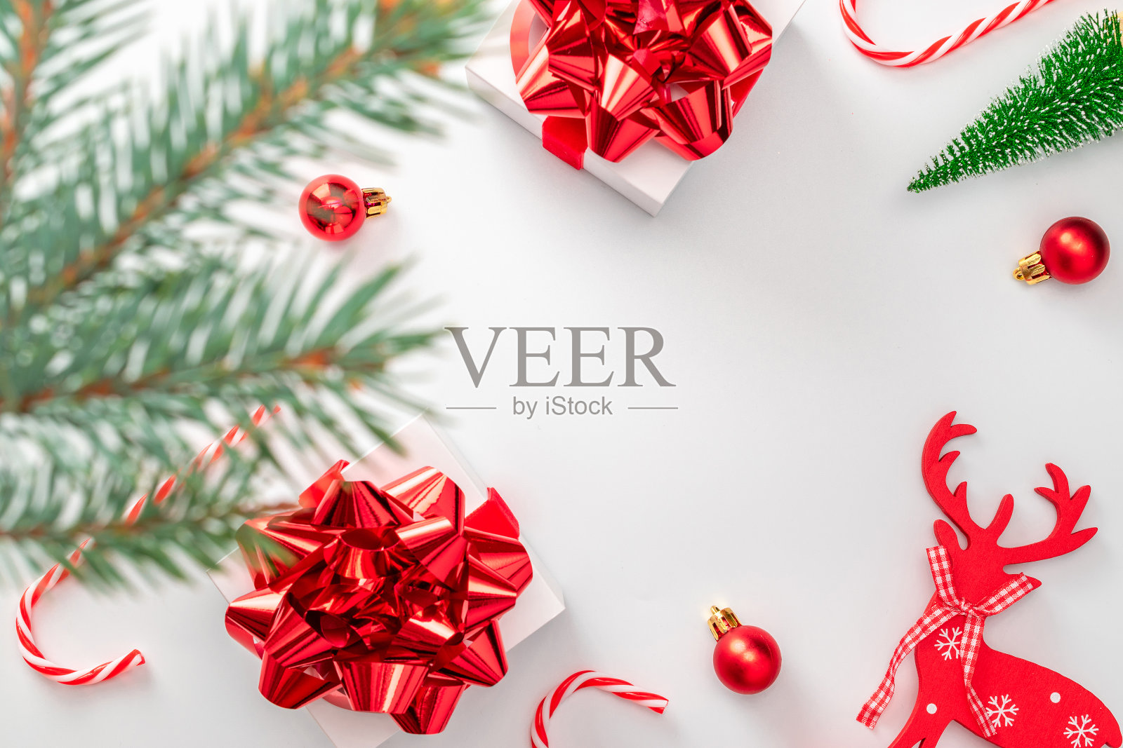 冬季背景红色。白色礼物与红色的蝴蝶结，红色的球，糖果和冬天的树在圣诞节装饰白色的背景贺卡。冬季节日构图用拷贝空间。照片摄影图片