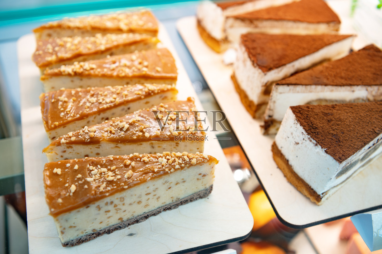 咖啡馆橱窗里的奶油蛋糕。撒上小坚果。切成三角形的蛋糕照片摄影图片