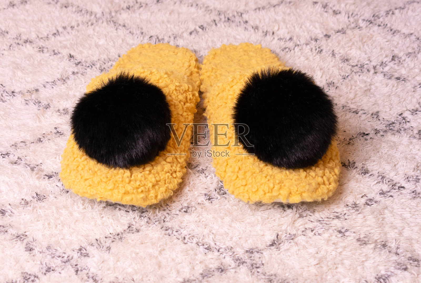 带大绒球的自制暖黄色拖鞋。特写镜头。照片摄影图片