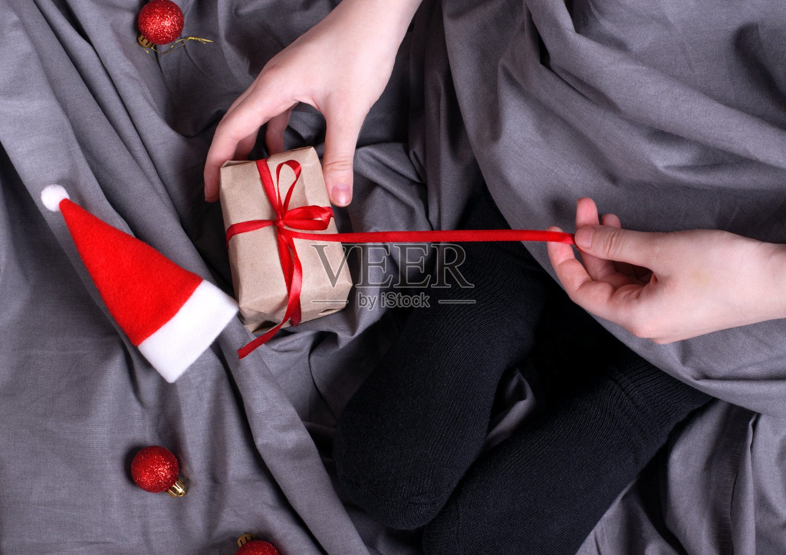 一名妇女坐在床上打开系着红丝带的礼品盒照片摄影图片