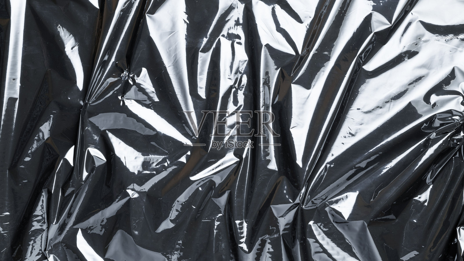 光滑的质地。黑色闪亮的薄膜袋图案。包裹透明的黑色玻璃纸背景。聚乙烯箔的真实质地。照片摄影图片