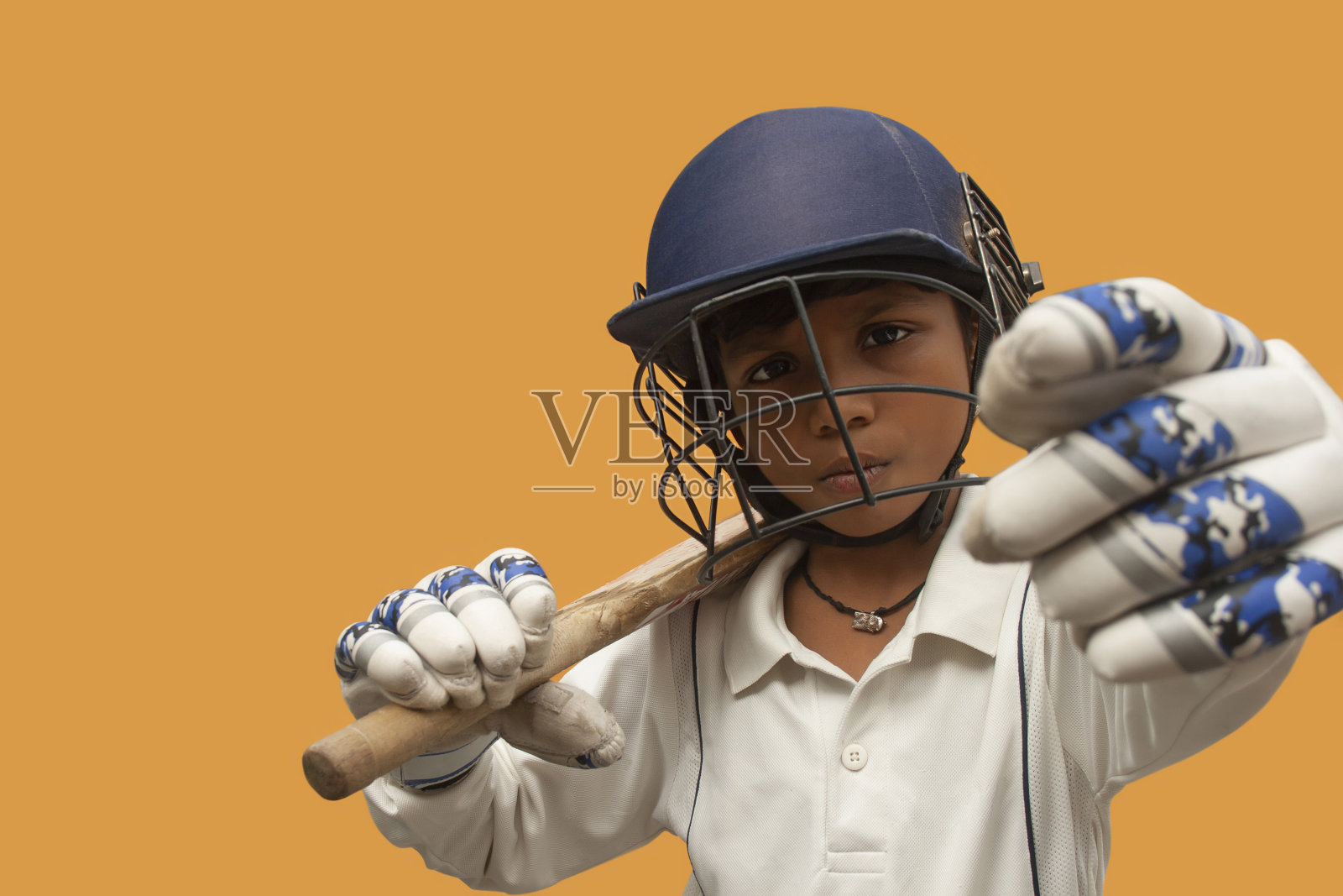 男孩的肖像戴着板球头盔和拿着球棒照片摄影图片