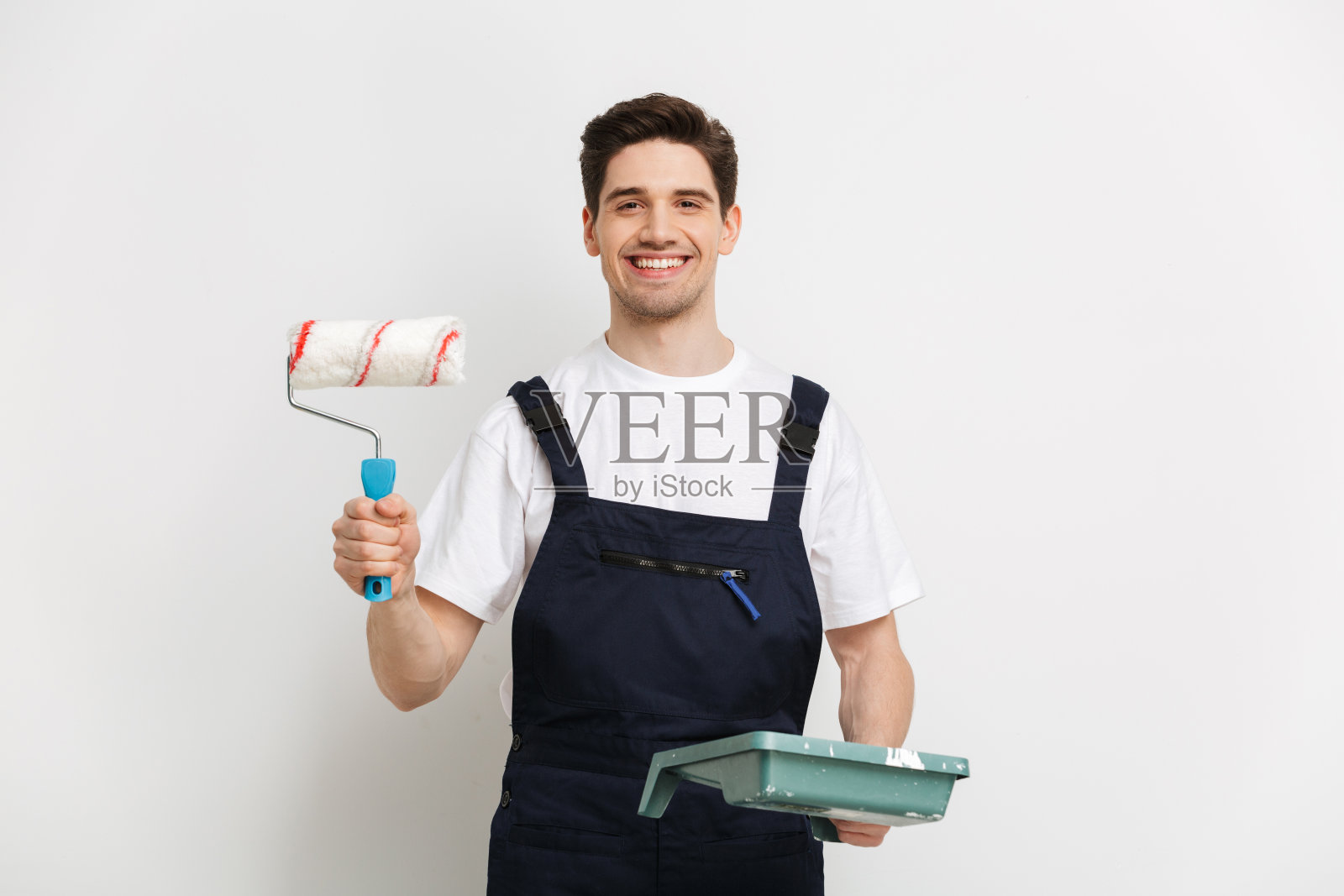 微笑的男性建筑工人展示油漆卷和看着相机照片摄影图片