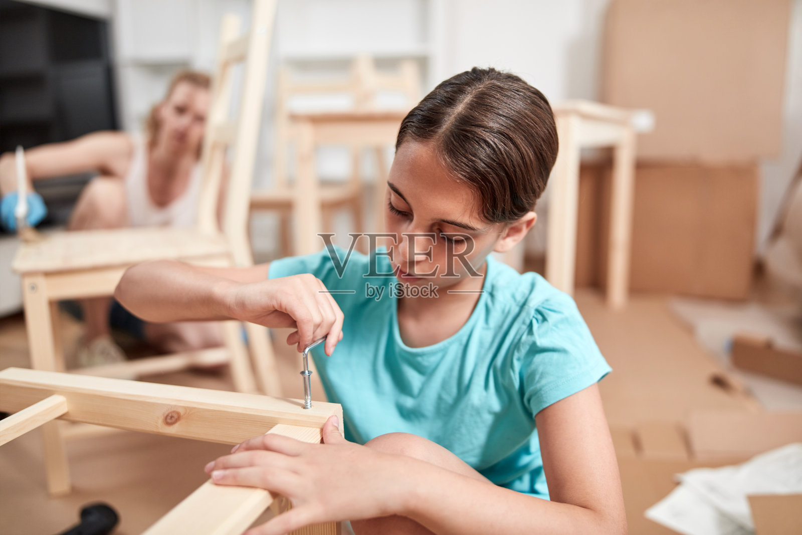 母亲和女儿在新公寓粉刷和组装家具，搬进来并努力工作。照片摄影图片