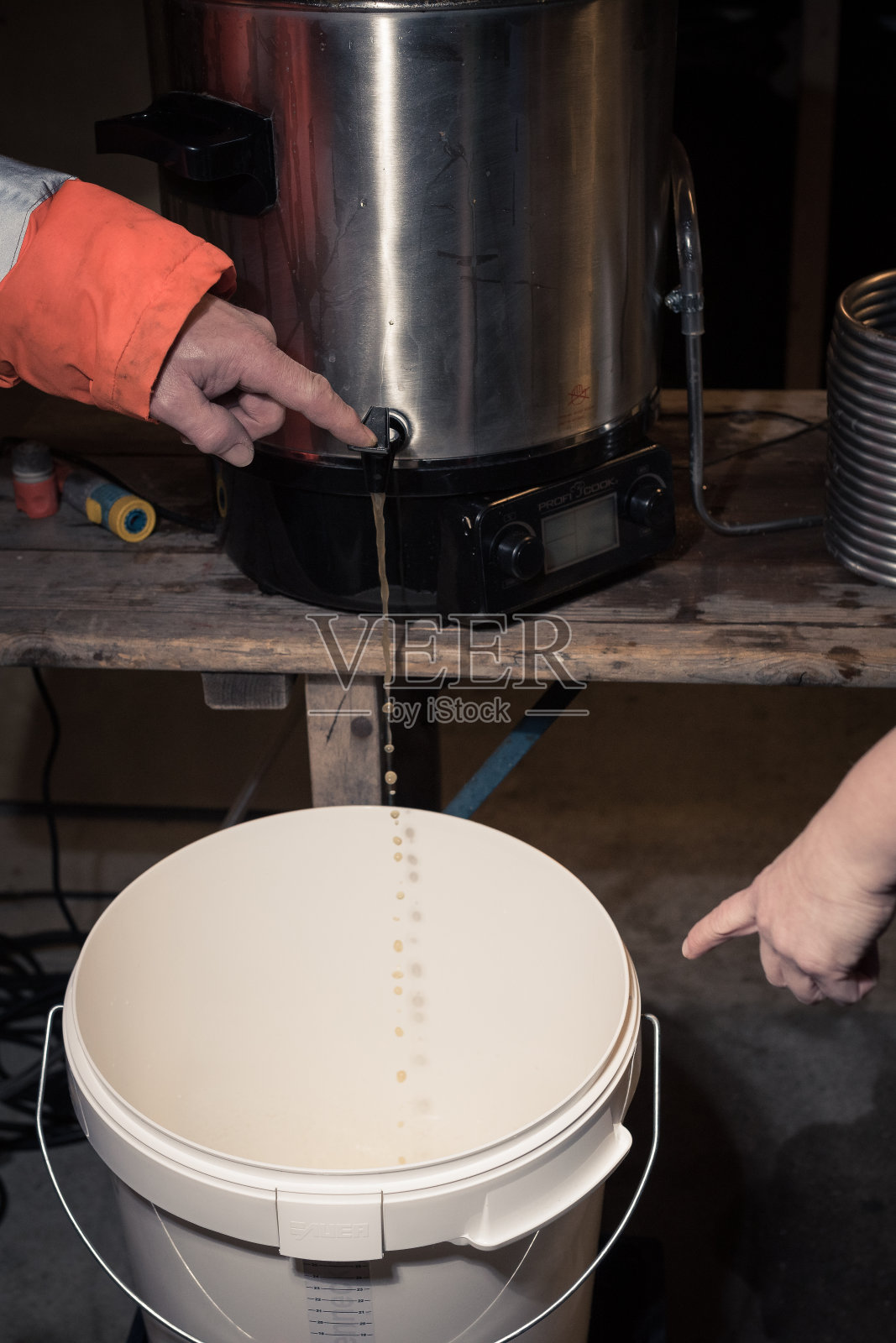 在家中车库啤酒酿造过程中，将新酿的啤酒倒入大桶中进行发酵照片摄影图片