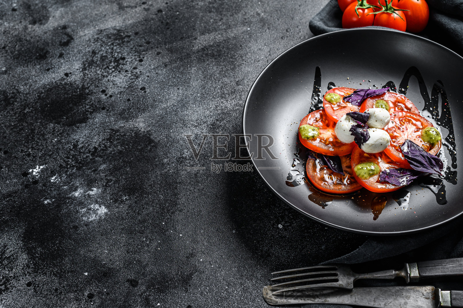 意大利传统卡普勒沙拉。圣女果，马苏里拉芝士，罗勒，香蒜沙司。黑色背景。前视图。本空间照片摄影图片