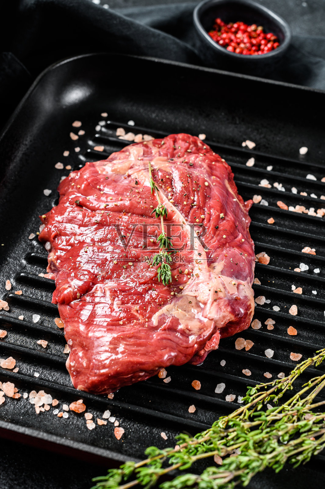 烤盘上的牛排，生肉，有花纹的牛肉。黑色背景。俯视图照片摄影图片