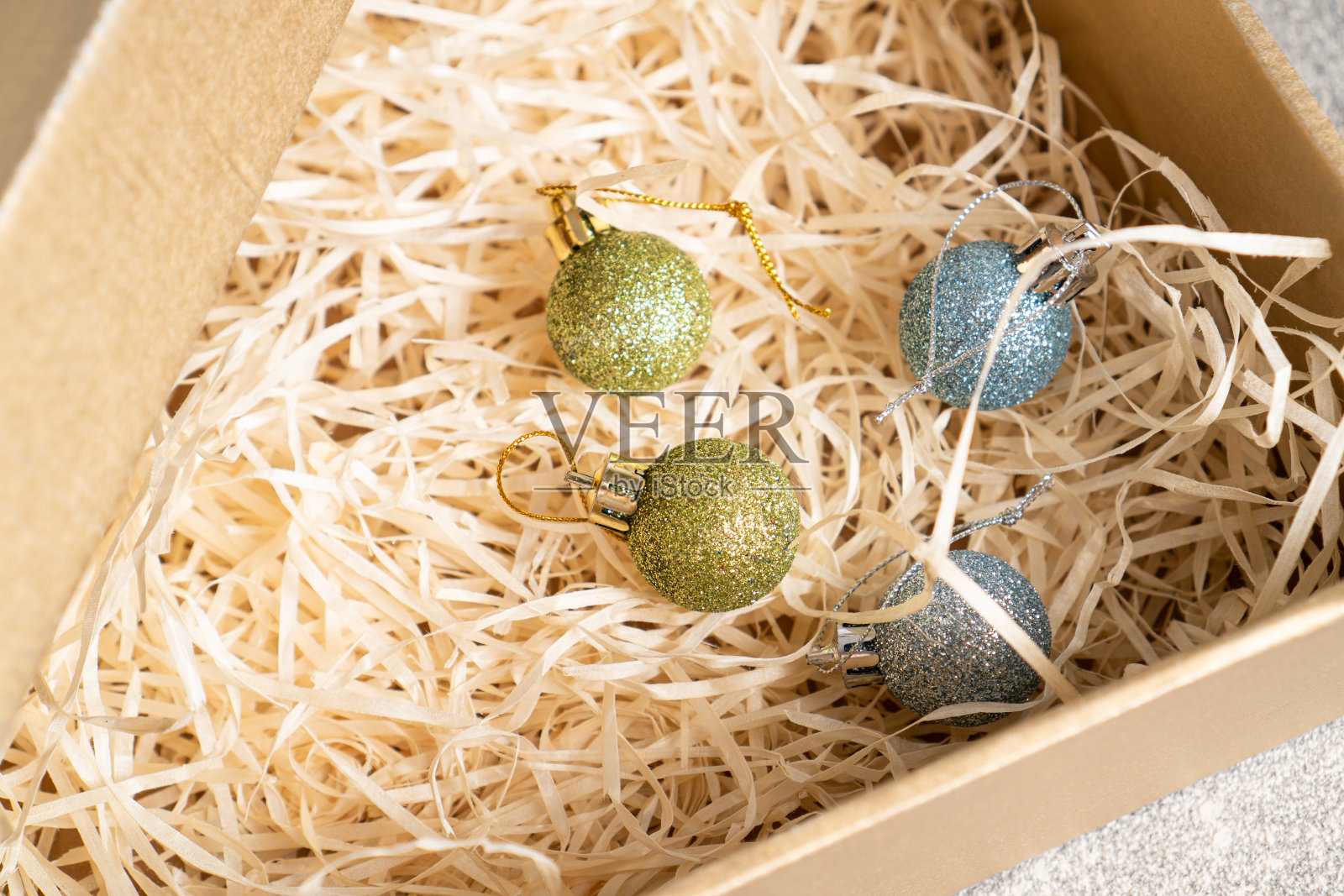 闪闪发光的圣诞树装饰品装在装满干木丝的盒子里。礼物盒子。碎木。冬天的背景照片摄影图片