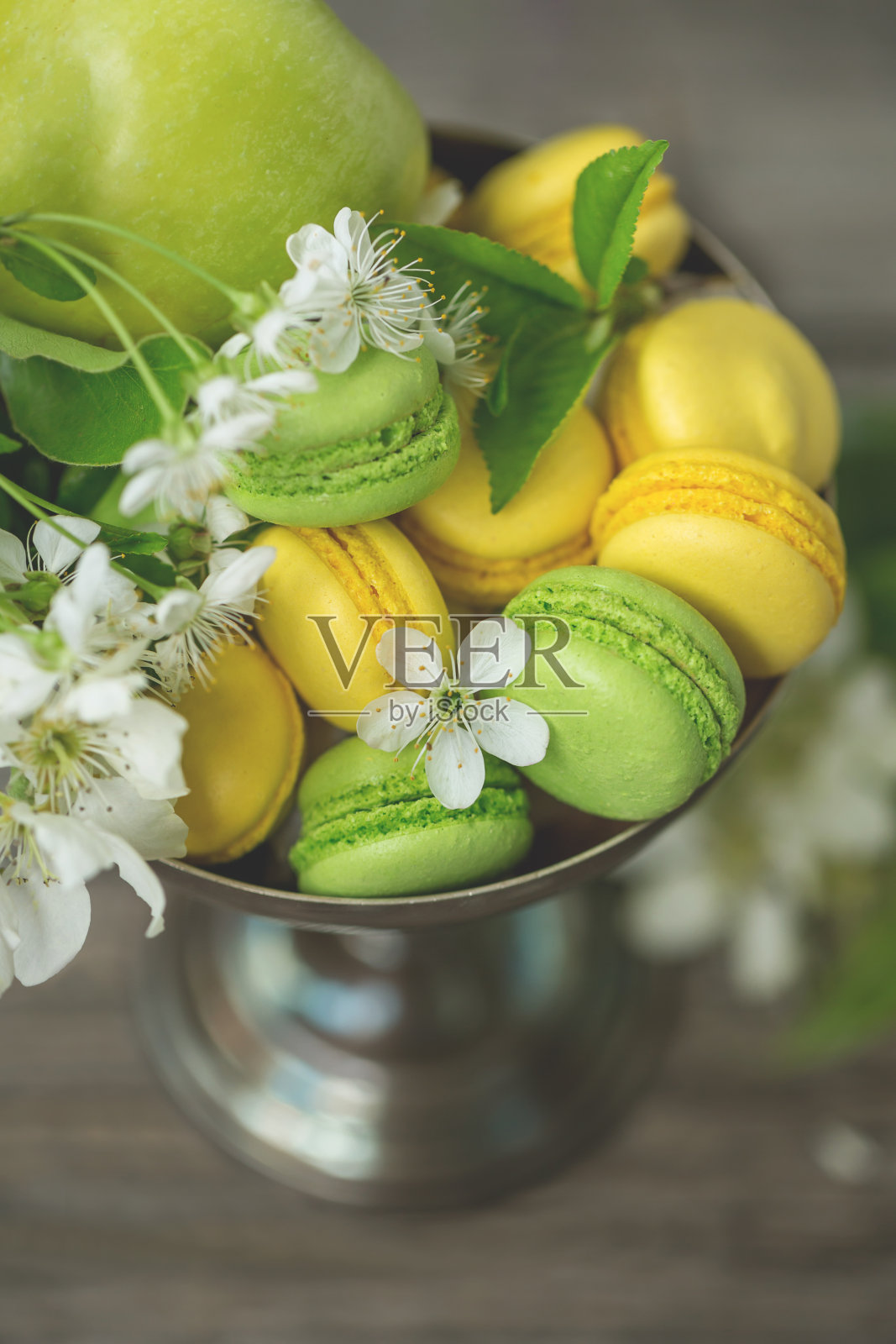 花瓶里有黄色和绿色的杏仁糖和樱花。照片摄影图片