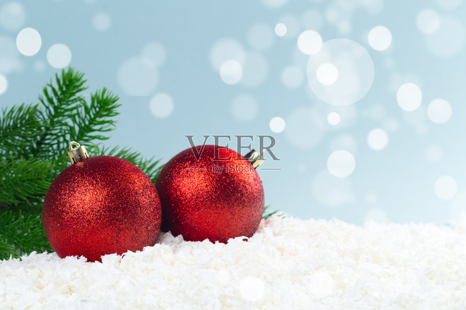 这是一棵圣诞树的树枝，上面有雪花中的圣诞球，背景是蓝色的，还有散景灯。新年贺卡照片摄影图片