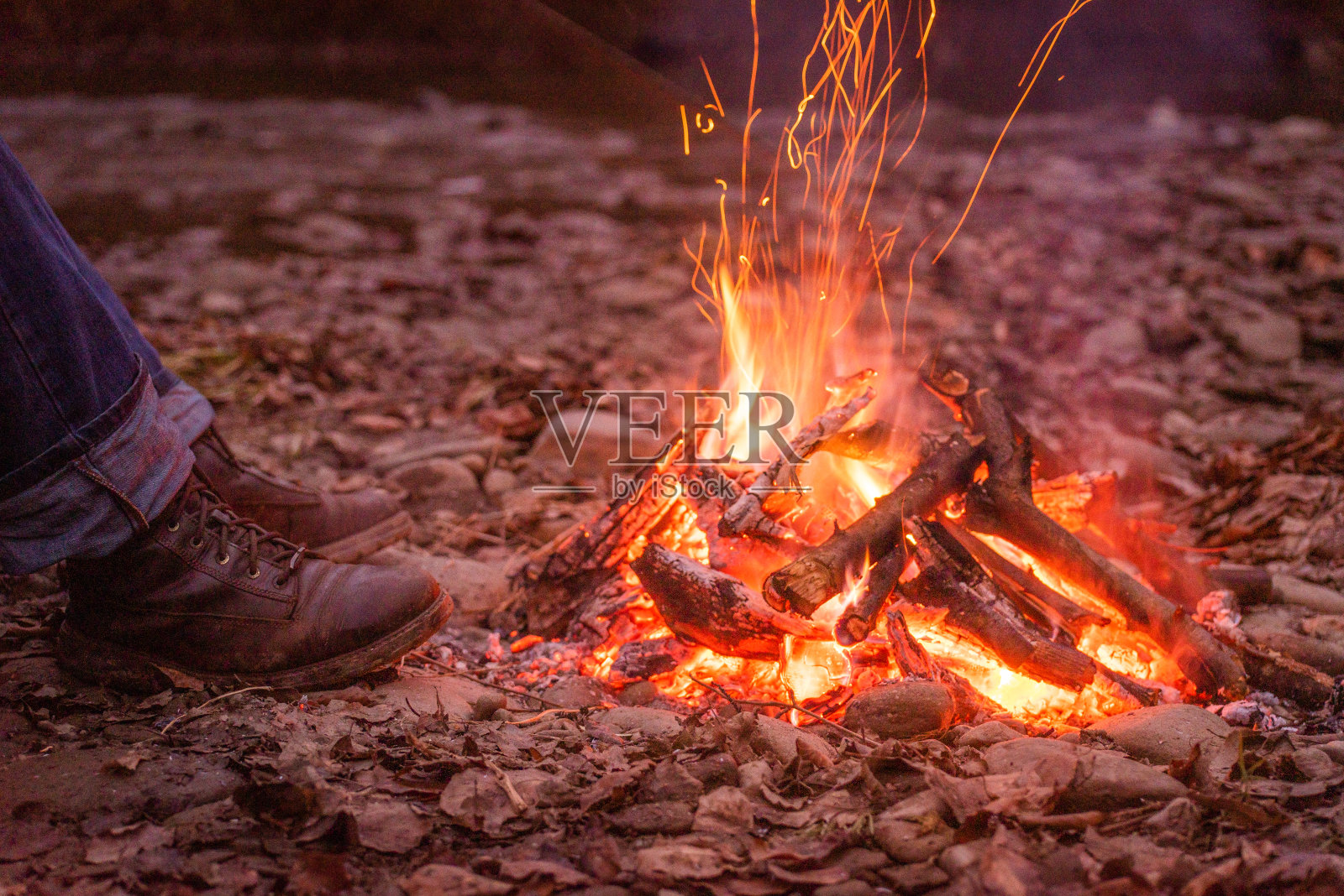 男人的靴子在夜火旁照片摄影图片