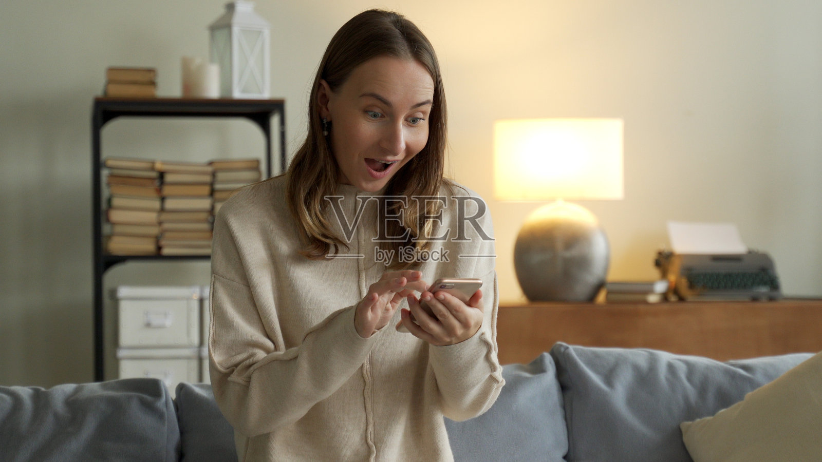 女人通过手机得到好消息通知。女孩用手机在网上庆祝胜利照片摄影图片