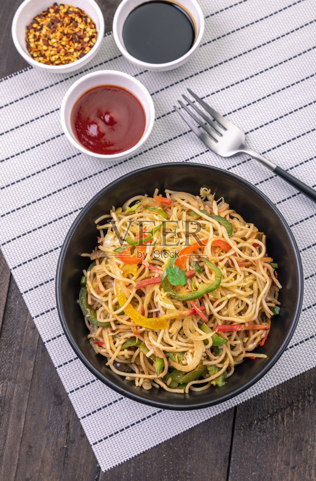 在黑碗里炒素面，加酱汁照片摄影图片