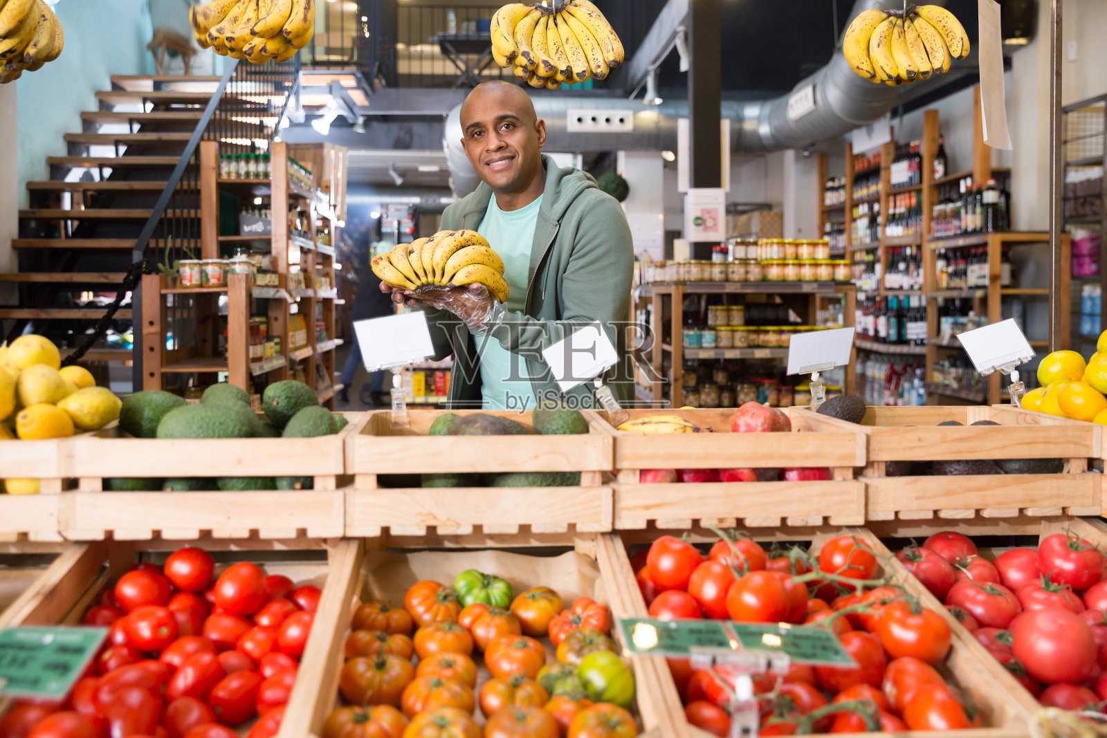西班牙男子在超市的水果和蔬菜区选择香蕉照片摄影图片