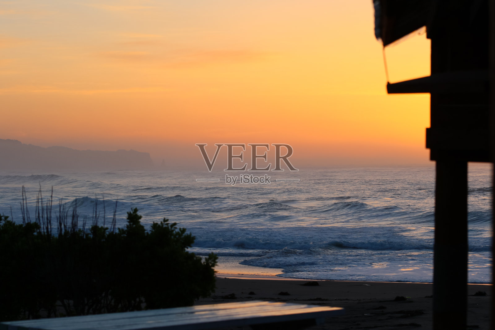 薄雾日出在日本海滩与大波浪打破照片摄影图片