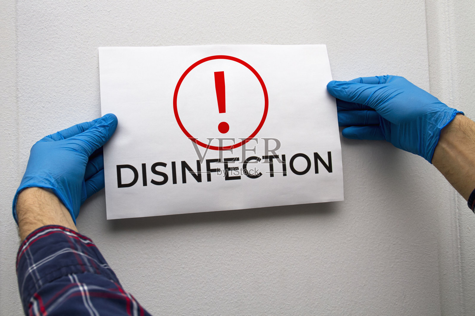 一名戴着蓝色防护手套的男子在门上贴了一张消毒通知照片摄影图片