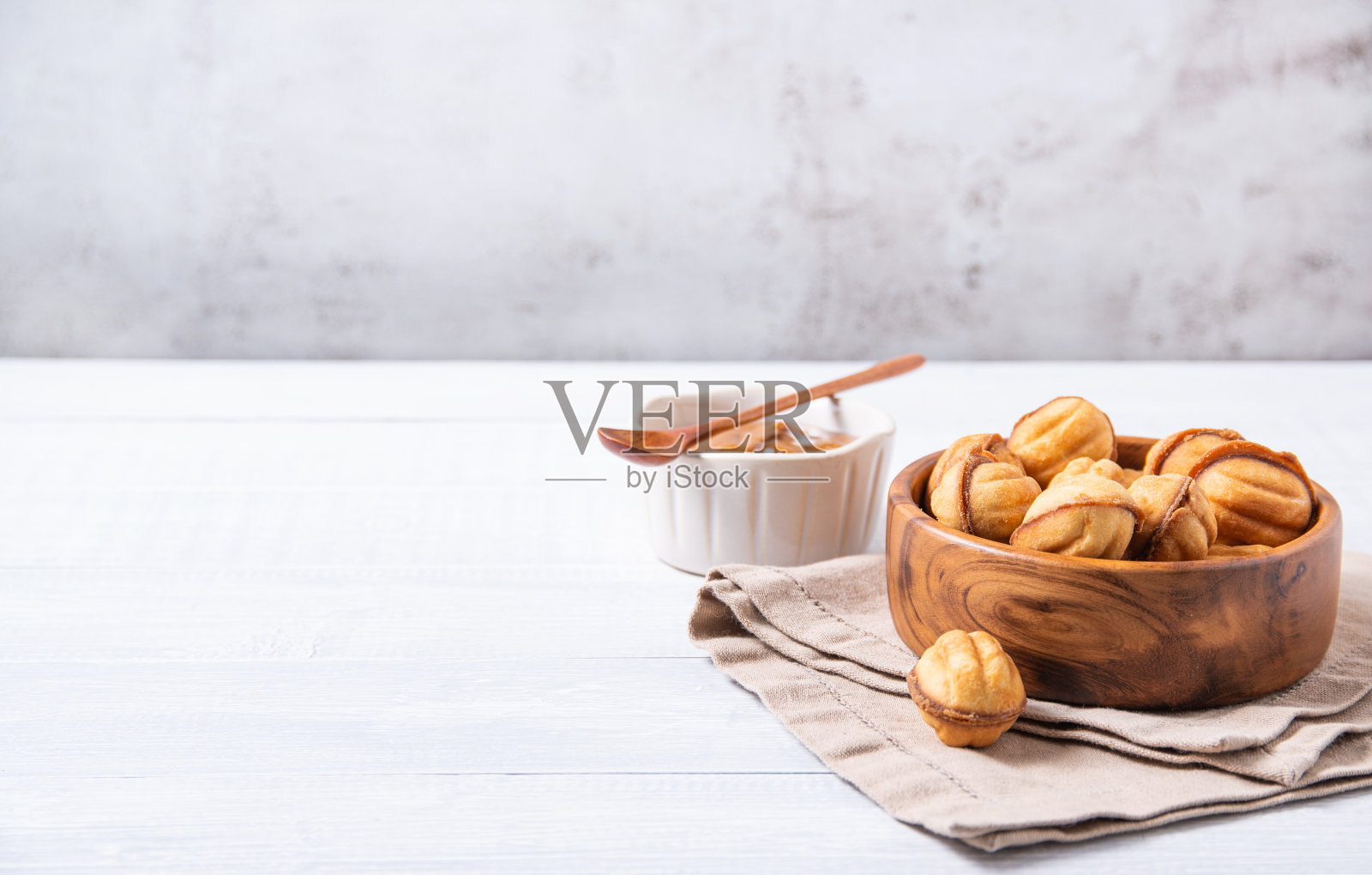 白色的桌子上，木碗里烤焦糖坚果照片摄影图片