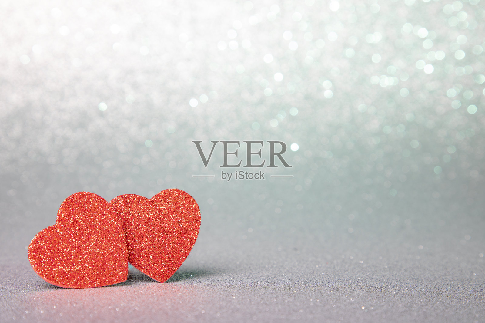 两颗闪闪发光的红心在银色的闪闪发光的背景上照片摄影图片