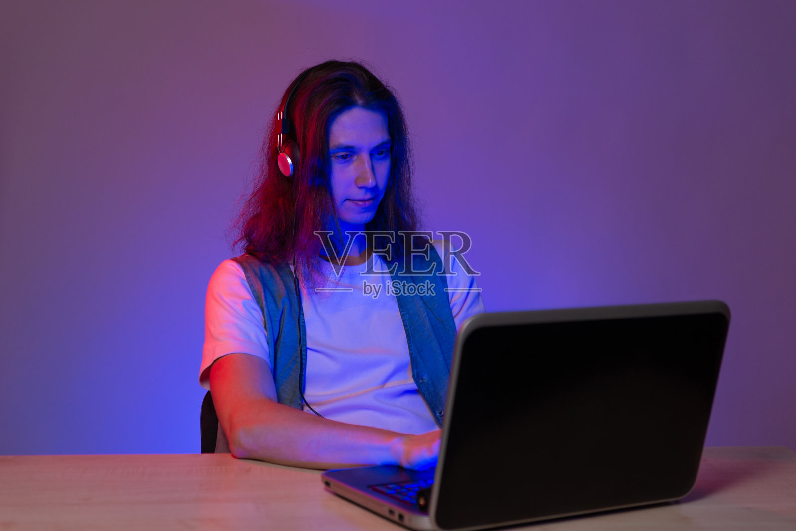 学生或程序员在笔记本电脑前，用霓虹灯绘制肖像。有趣的极客写代码。照片摄影图片