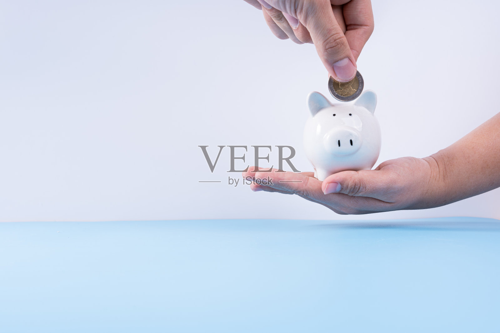 手把硬币放入存钱罐孤立的灰色背景。物业投资和房屋抵押的金融概念。照片摄影图片