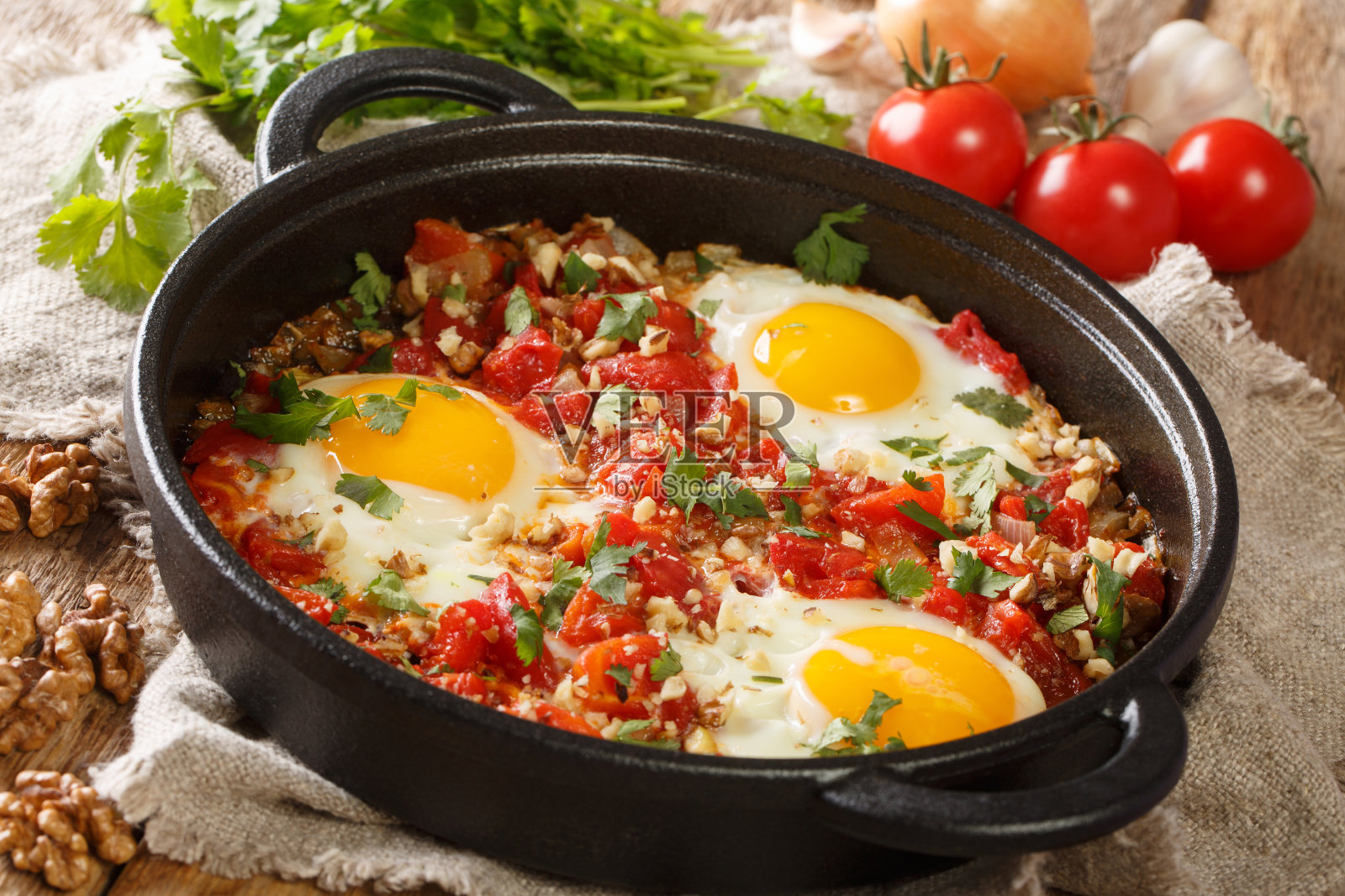 Chirbuli是格鲁吉亚早餐餐桌上的主食，里面有煎蛋、西红柿、洋葱和核桃，近距离地放在煎锅里。水平照片摄影图片