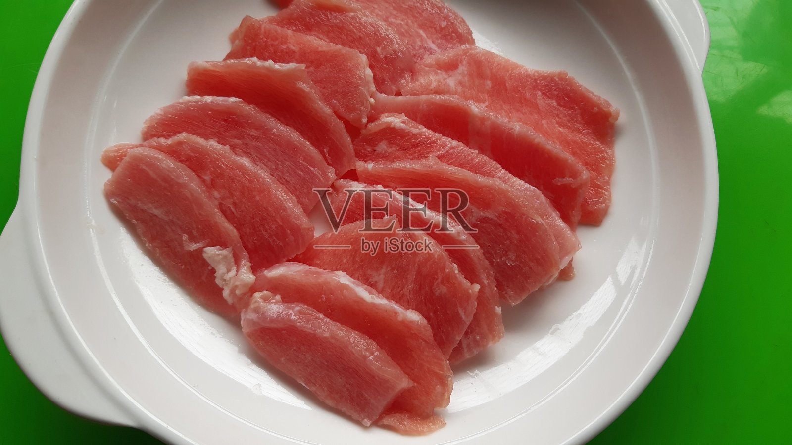 把猪肉切成片放在盘子里。照片摄影图片