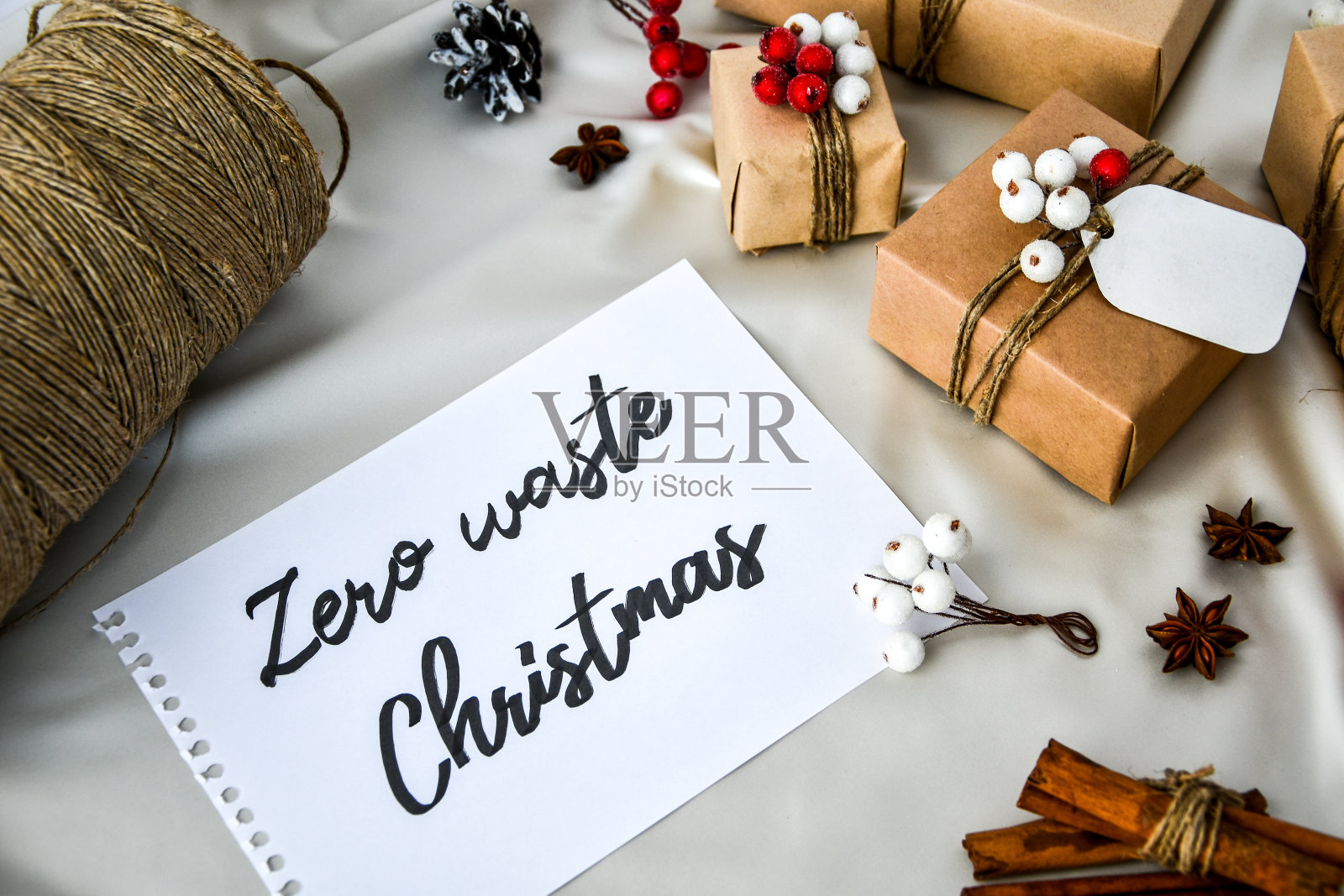 零浪费的圣诞文字与礼物装饰在香槟色的丝绸背景。副本的空间。环保包装礼品与标签从工艺纸板照片摄影图片