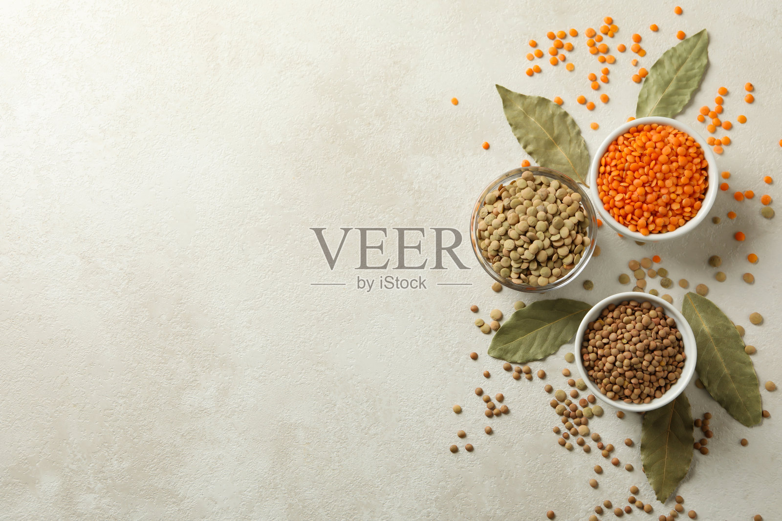 碗与不同的豆类和月桂叶在白色纹理的背景照片摄影图片