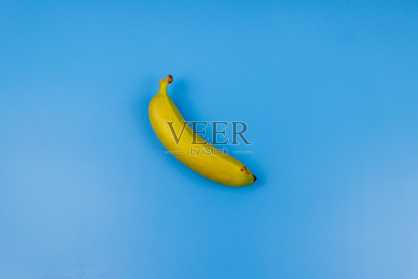 淡蓝色背景上的黄色香蕉。俯视图，平面铺设，最小的设计照片摄影图片