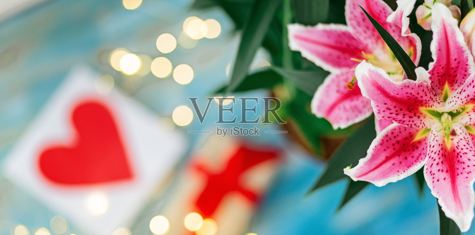 情人节的概念与丁香花束和包装的礼物心形卡片上蓝色的木制桌子照片摄影图片