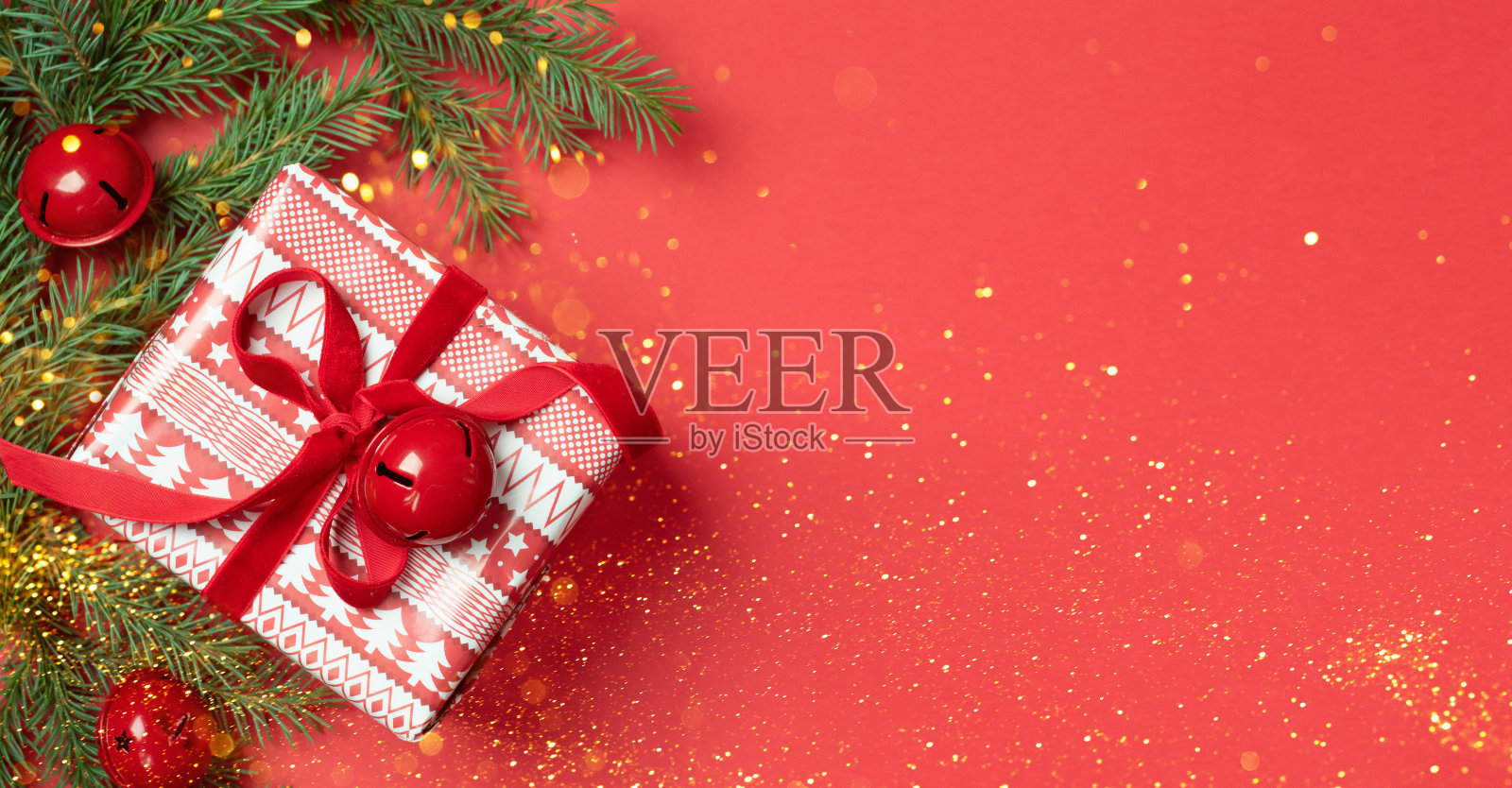 礼盒红色蝴蝶结云杉枝红色背景。新年或圣诞节的横幅照片摄影图片