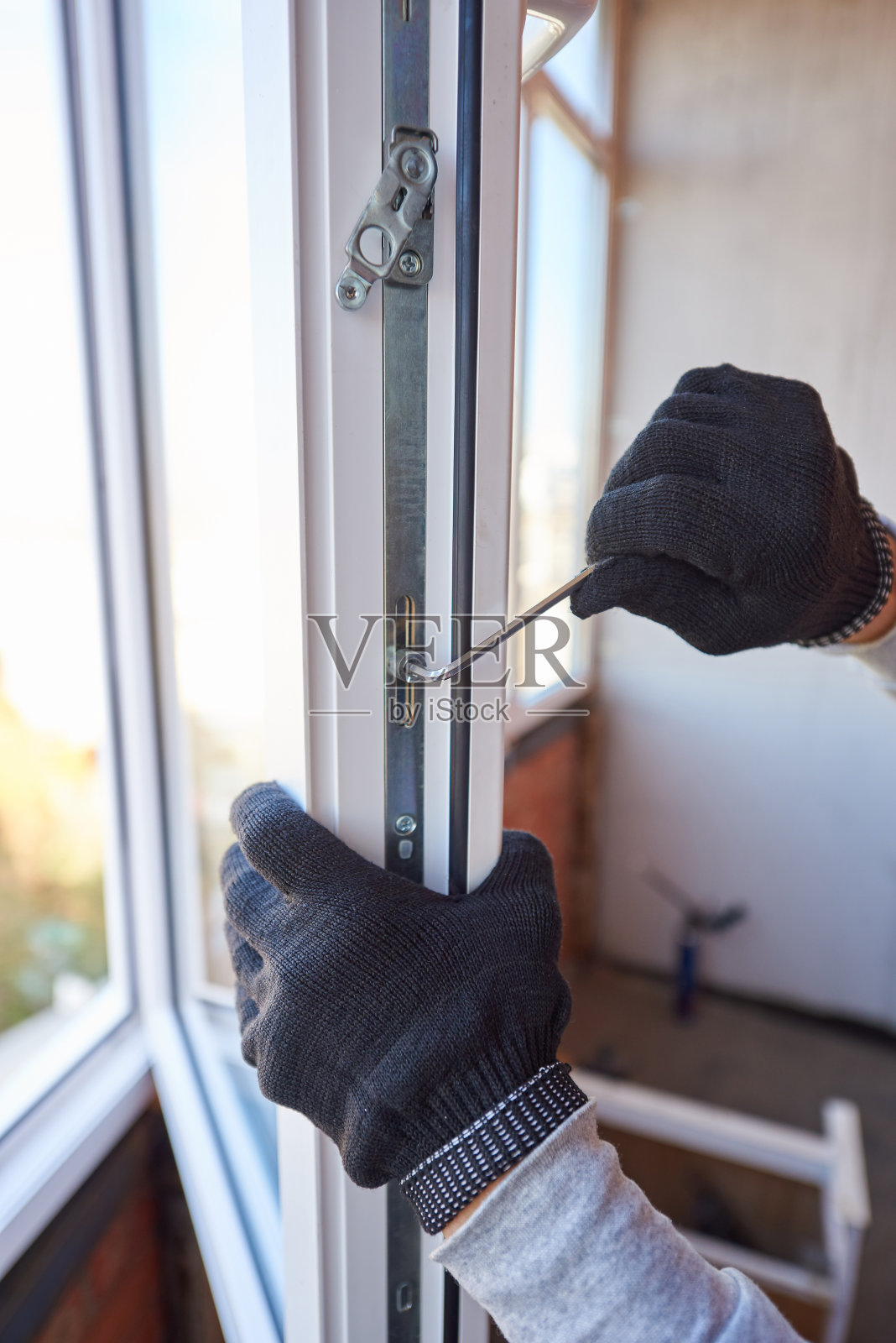 一个工人的手的特写调整一个新的塑料窗口。照片摄影图片