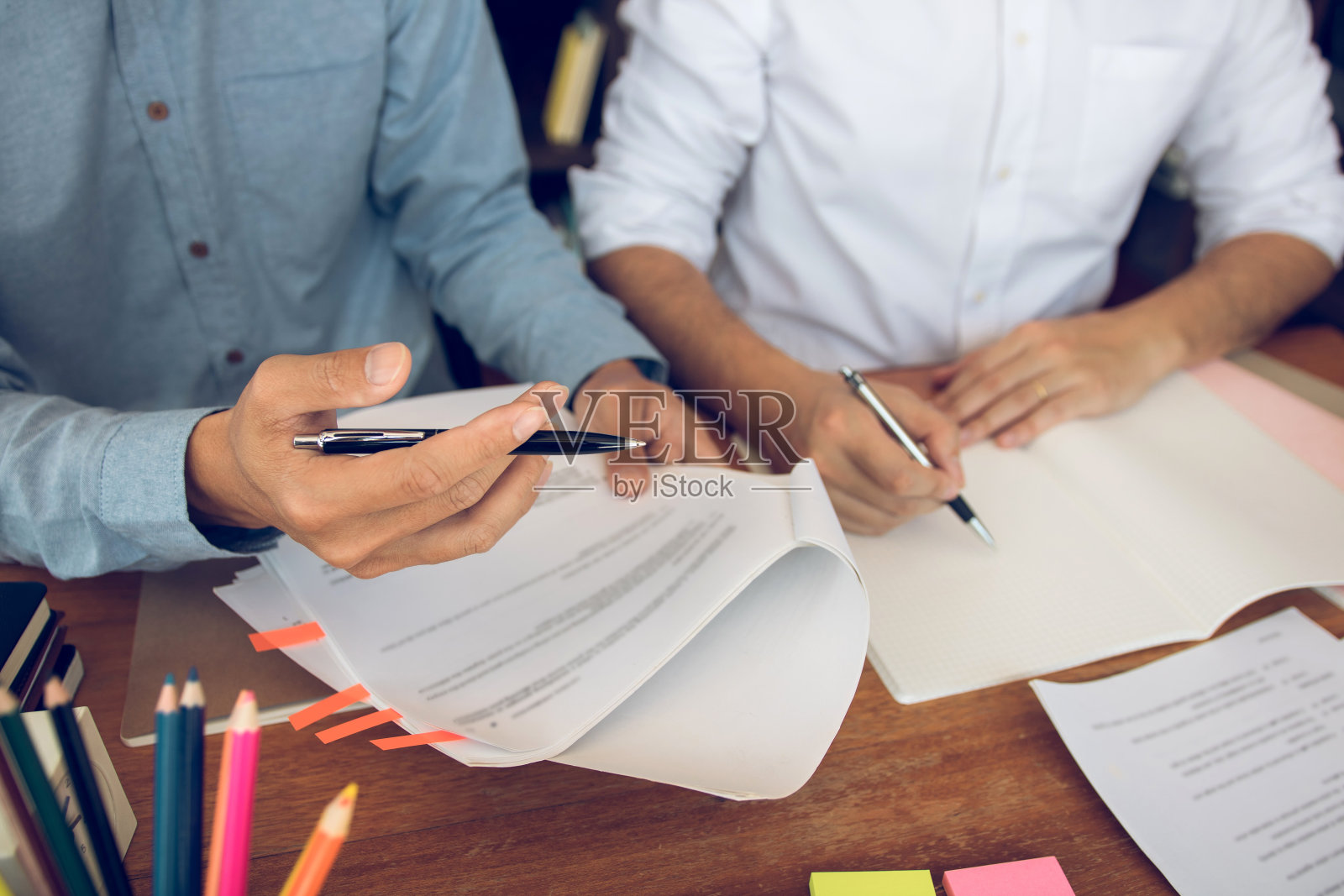 亚洲年轻大学生坐在图书馆的书桌前一起学习。照片摄影图片