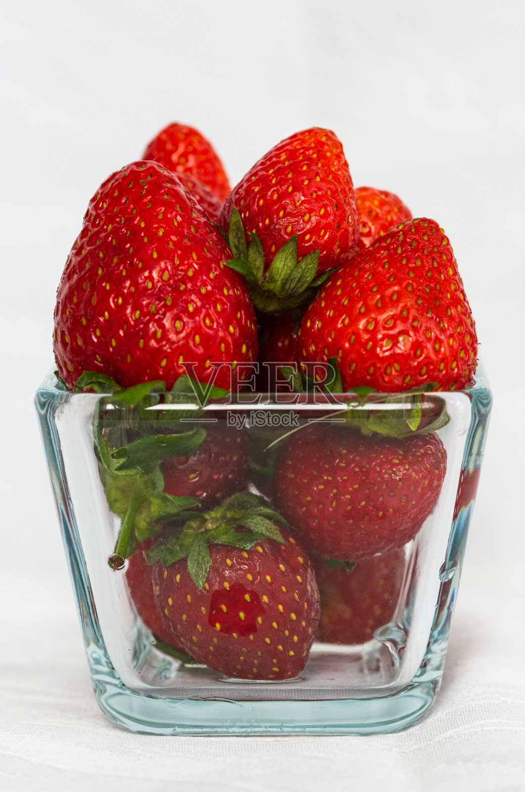 白色背景上的玻璃碗里的草莓照片摄影图片