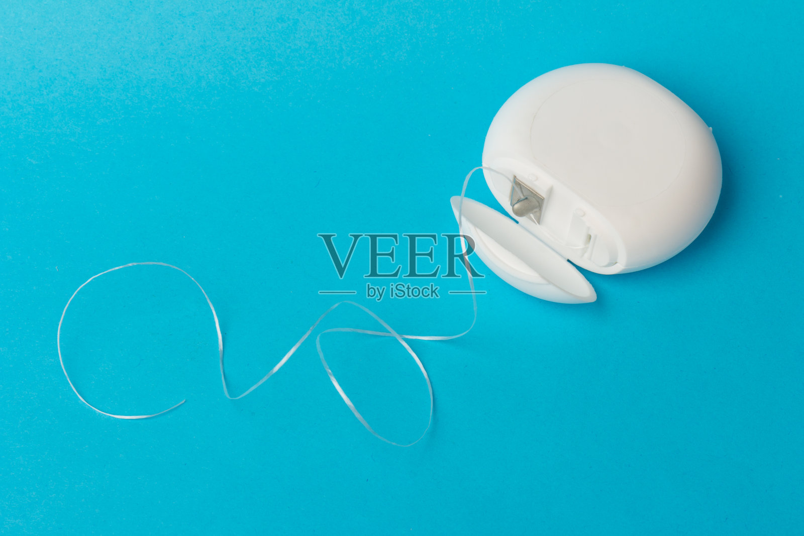 蓝色背景上的牙线容器。日常口腔卫生，牙齿保健和健康。口腔清洁用品，拷贝空间。牙科保健的概念。照片摄影图片