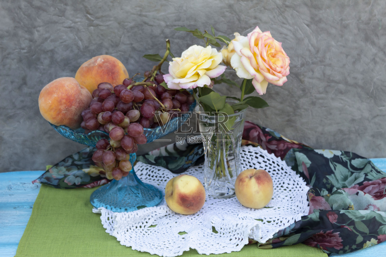 一瓶玫瑰，旁边放着两个桃子，还有一瓶葡萄和桃子。照片摄影图片
