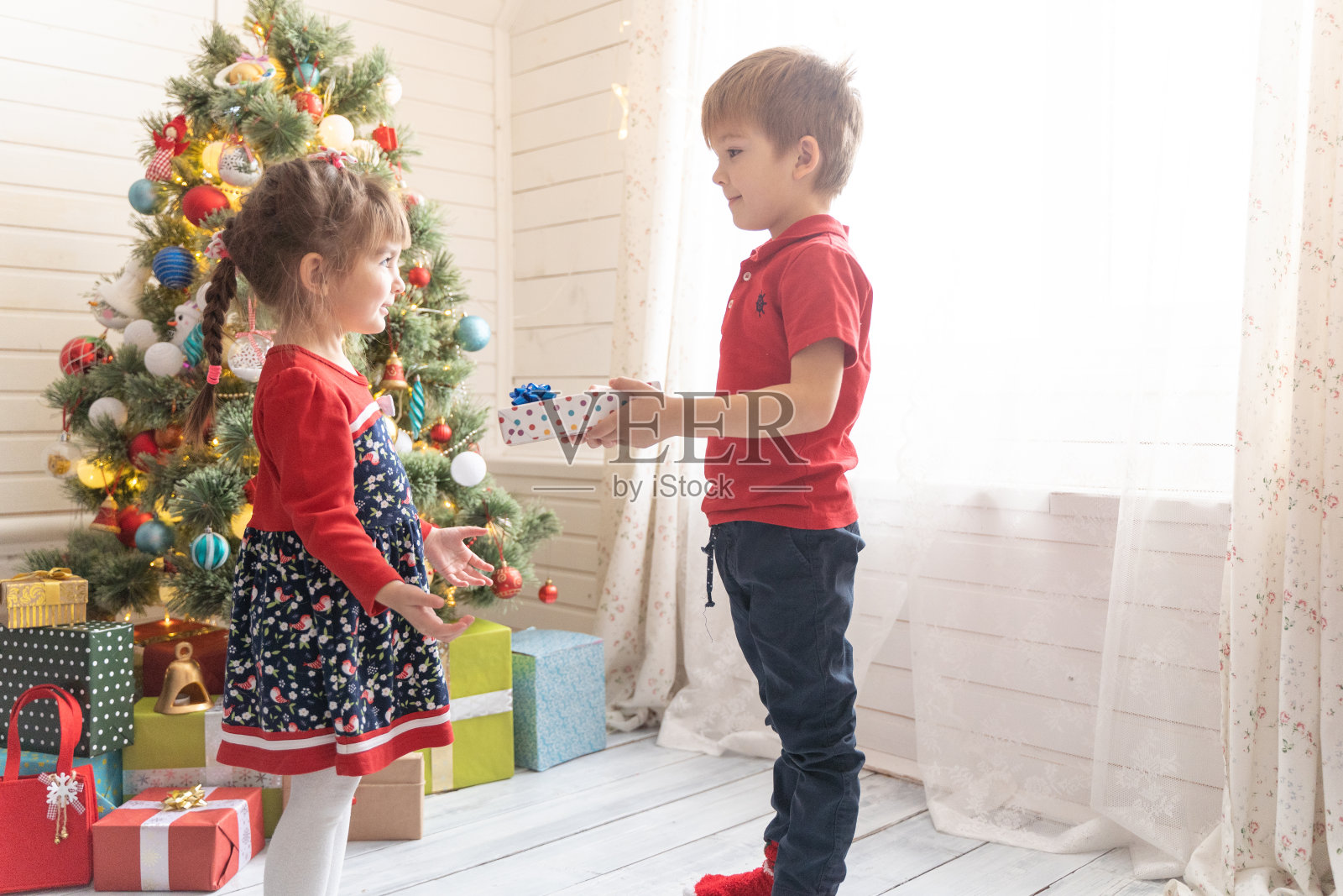 在一个阳光明媚的房间里，男孩给了一个女孩一份圣诞礼物照片摄影图片
