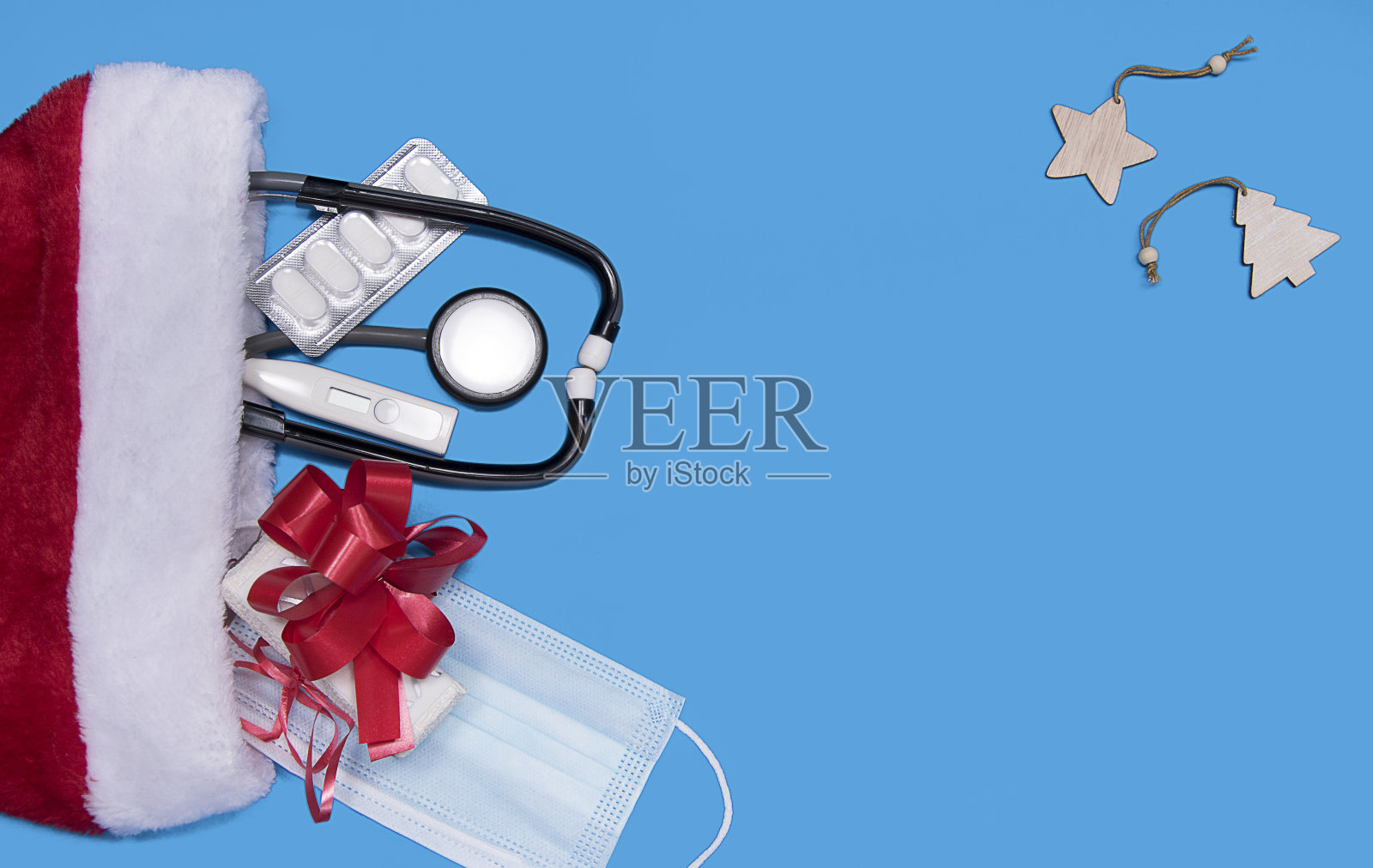 医学圣诞旗帜与药丸，礼物礼物盒和圣诞老人帽子在蓝色的背景。33、药新年平躺，贺卡问候。照片摄影图片