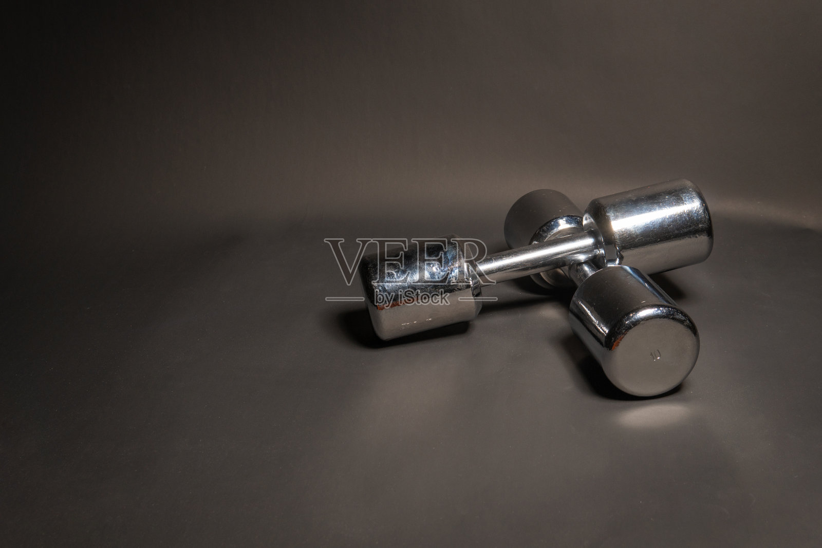 健身哑铃，在黑色背景下闪耀着金属色照片摄影图片