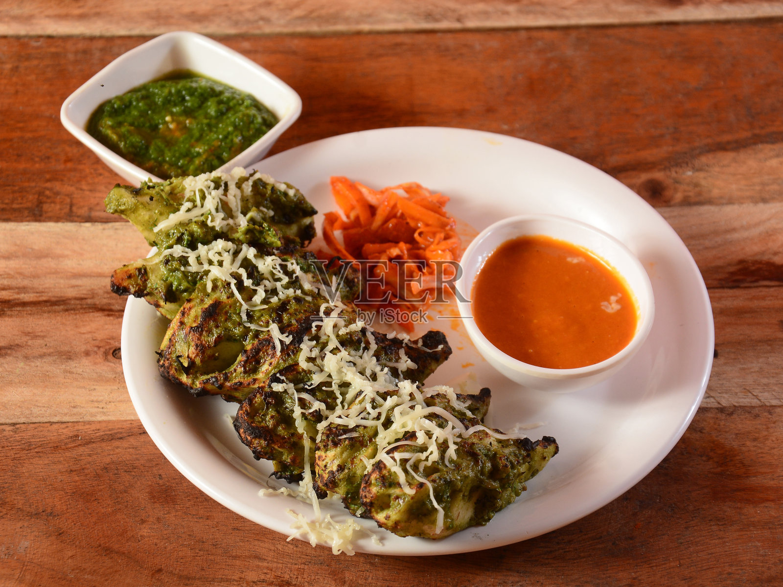 鸡肉咖喱馍配酱汁和薄荷酸辣酱，配以质朴的木质背景，选择性的聚焦照片摄影图片