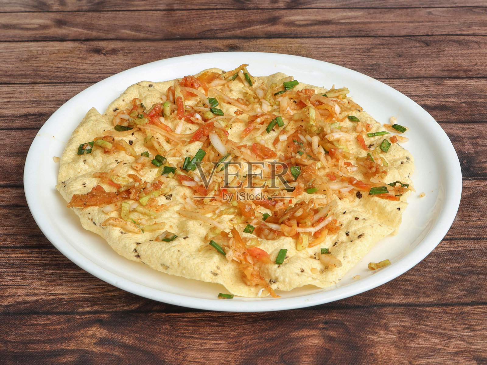 Masala Papad是一种美味的印度小吃，用烤或炸的Papad上撒上辛辣的洋葱番茄混合物，配以乡村的木质背景，选择性地聚焦照片摄影图片