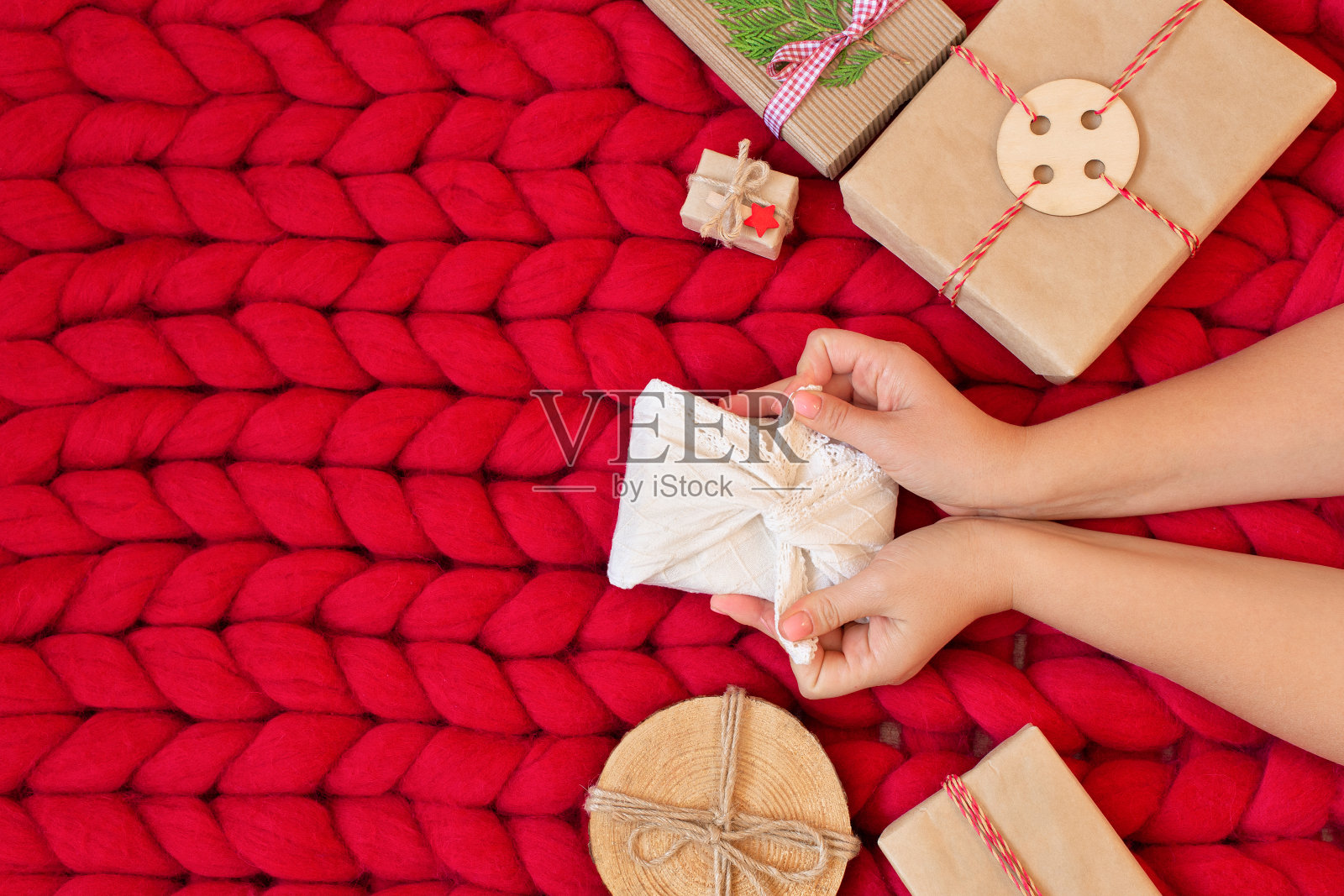 零浪费圣诞平躺。手握圣诞礼物的妇女在传统的日本Furoshiki风格亚麻织物上柔软的手编织美利奴羊毛毯子。塑料是免费的。生态装饰照片摄影图片