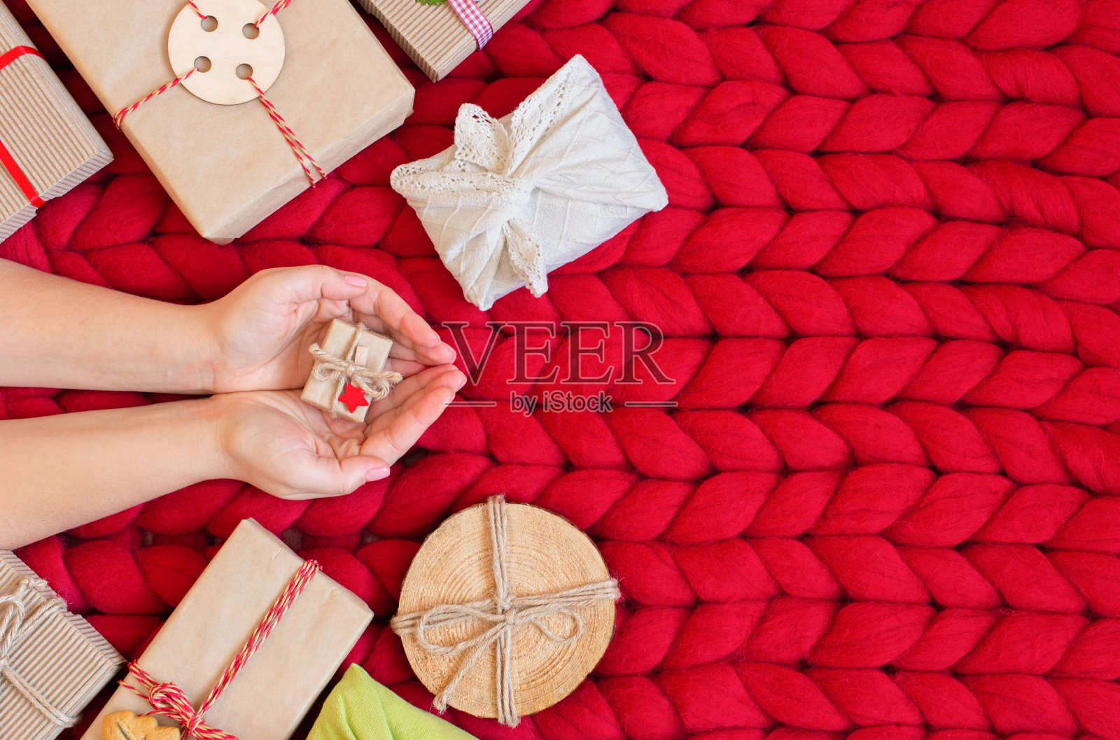 零浪费圣诞平躺。手握圣诞礼物在牛皮纸上的乡村风格在柔软的手编织美利奴羊毛毯子。生态装饰概念。塑料免费照片摄影图片