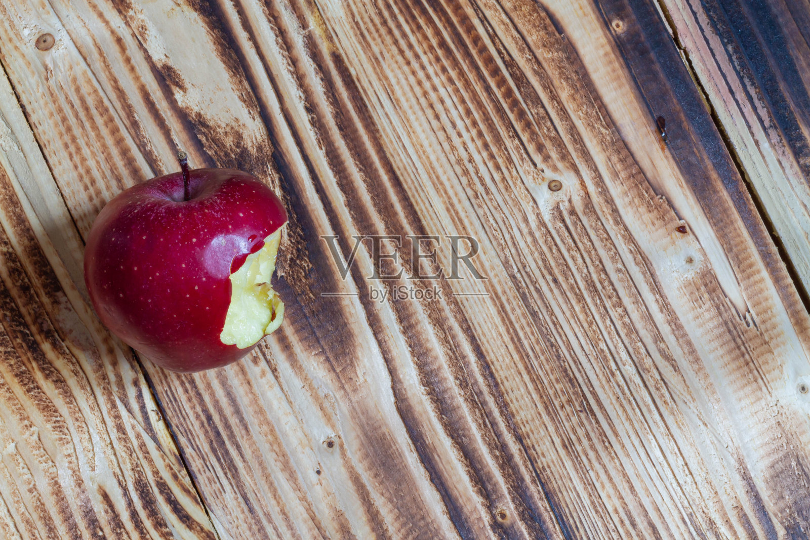 一个被咬过的红苹果放在木头背景上照片摄影图片
