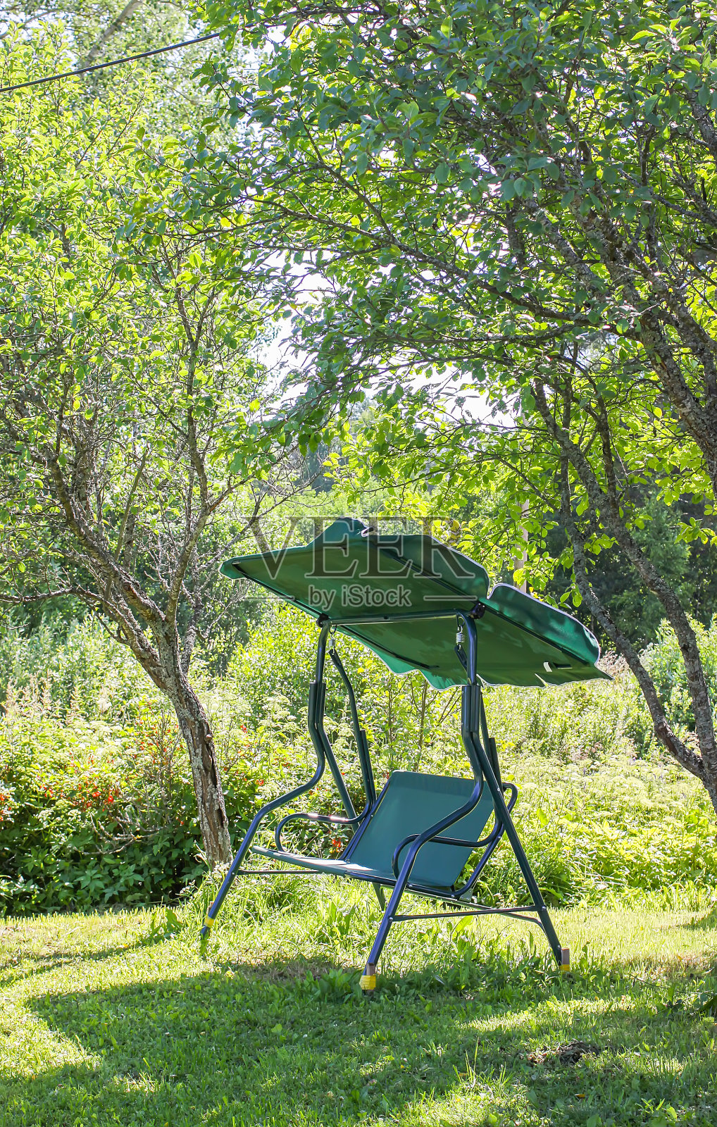 在阳光灿烂的日子里在夏日公园荡秋千。照片摄影图片