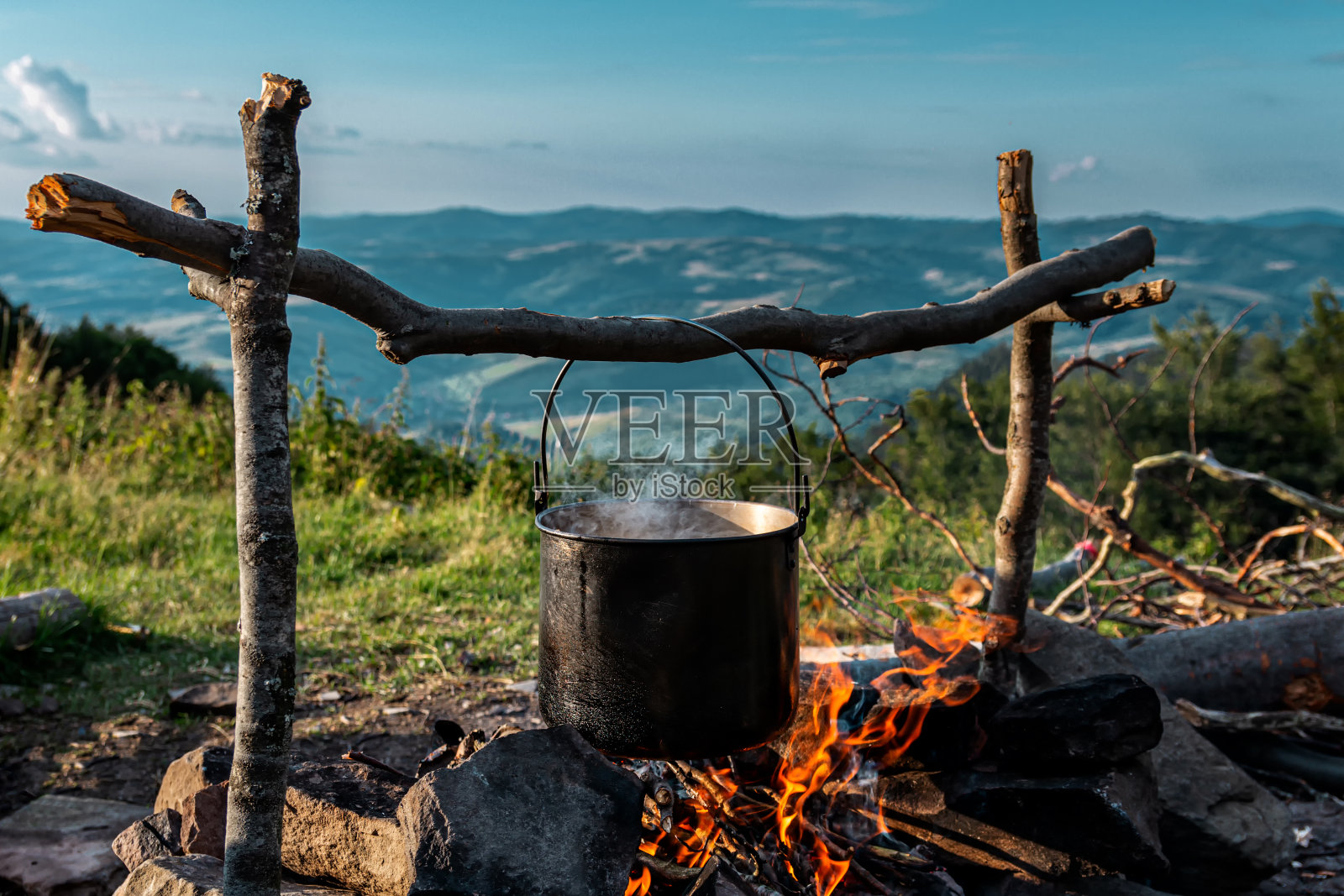 在火盆上。在营地准备食物。从营地看到的群山。照片摄影图片