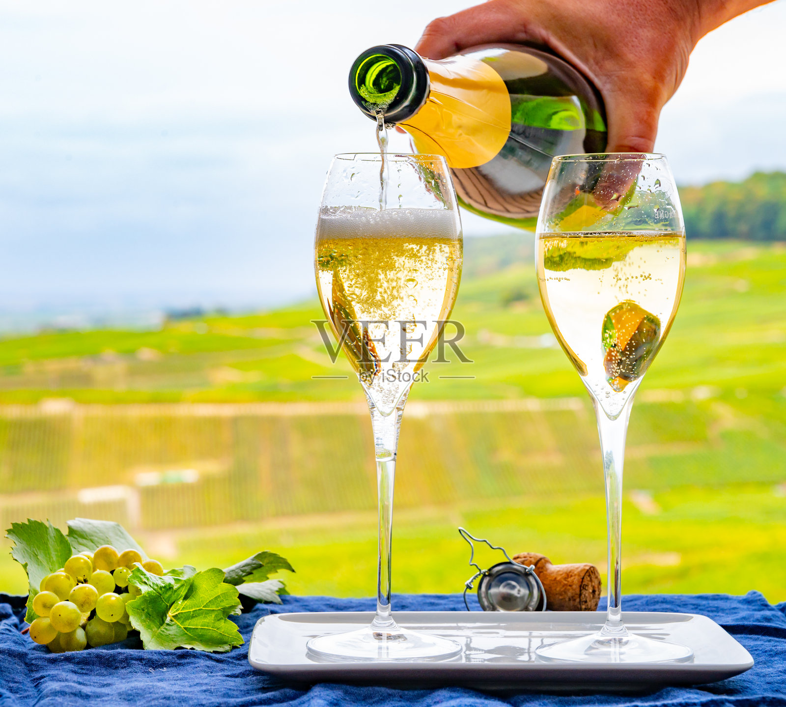 品尝法国起泡白葡萄酒与气泡香槟在室外露台上观看特级香槟葡萄园在克拉曼，靠近埃佩尔内，法国照片摄影图片