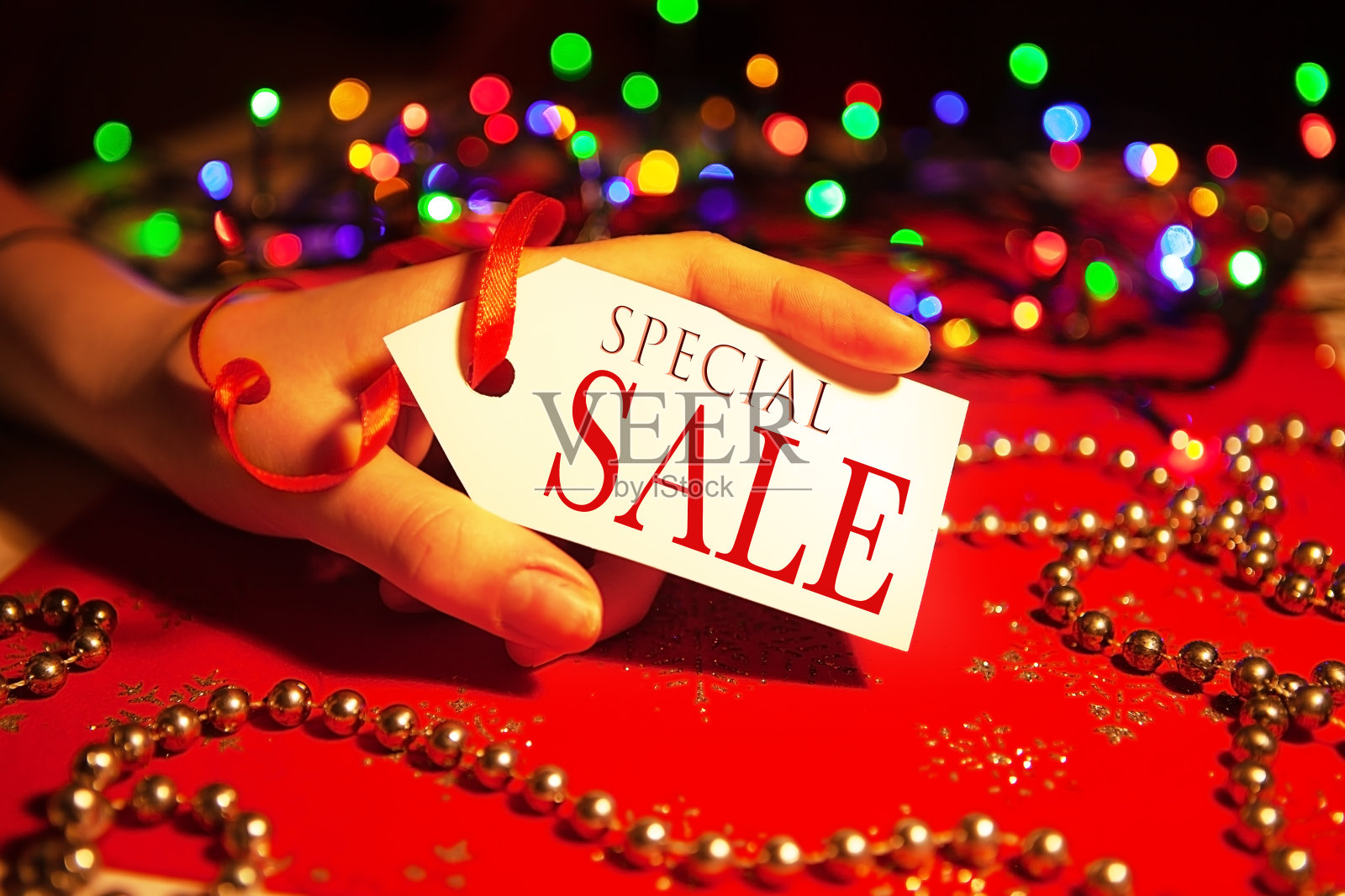 一名妇女手里拿着一个标签，上面写着圣诞节和新年假期期间的特别促销。照片摄影图片